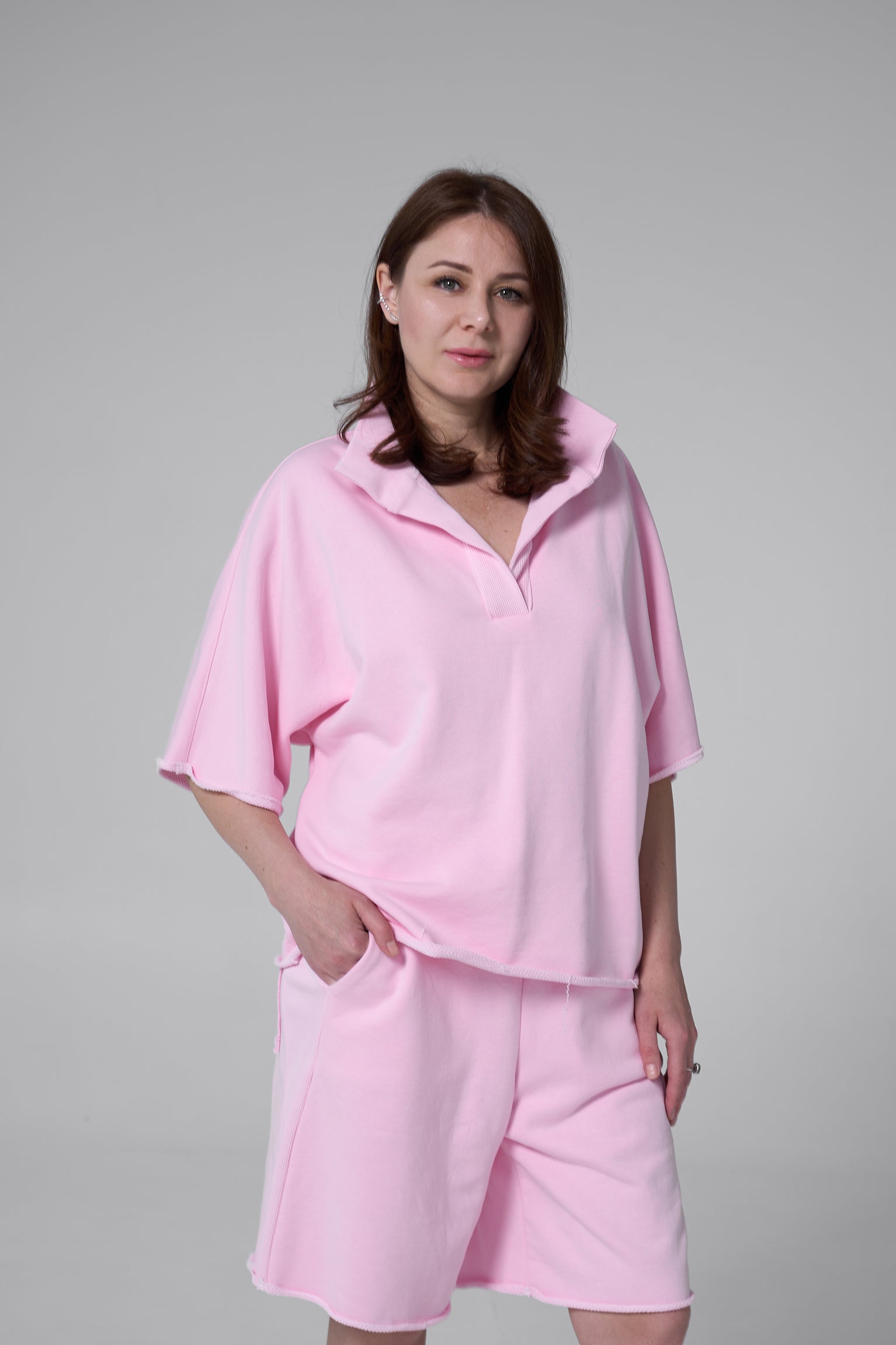 Woman wearing a pink outfit against a gray background pink