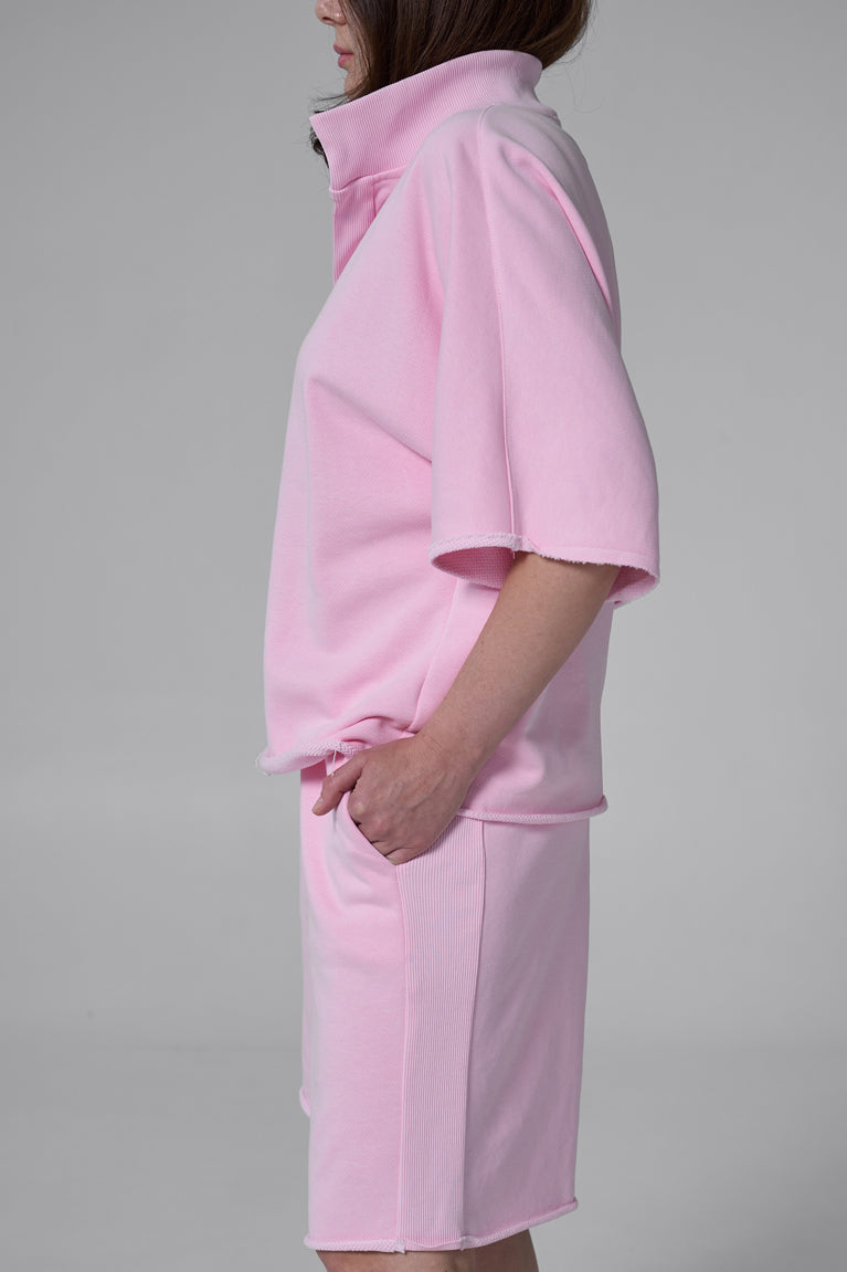 Person wearing a pink outfit on a gray background pink