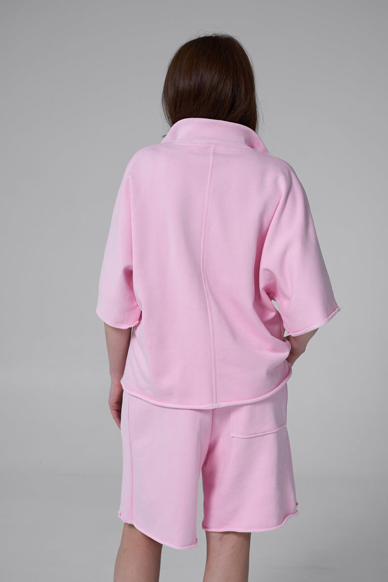 Person wearing a pink outfit with a gray background pink