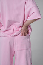 Person wearing a pink outfit with a plain background pink