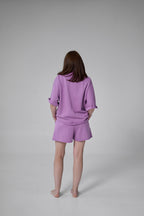 Person wearing a purple outfit on a gray background purple
