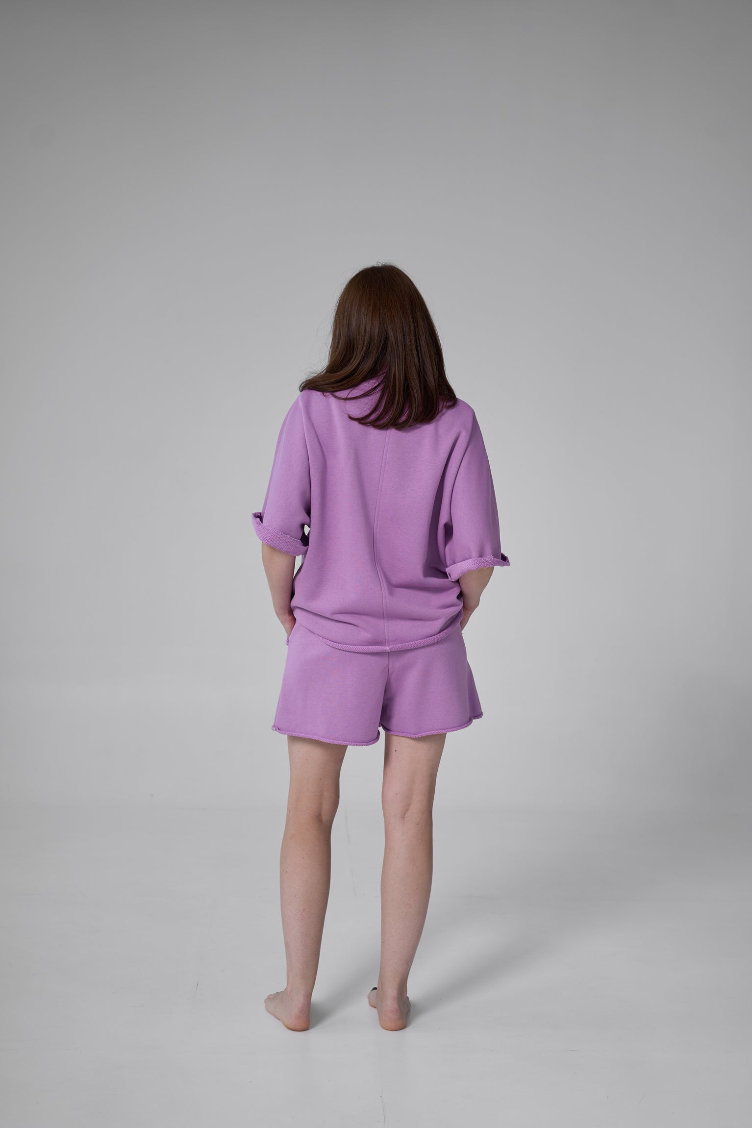 Person wearing a purple outfit on a gray background purple