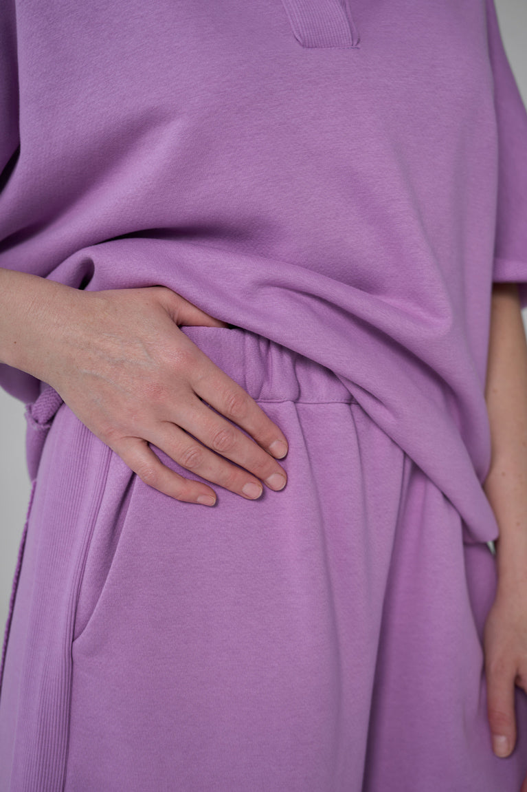 Purple oversized shirt worn by a person with a neutral background purple