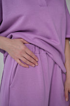 Purple oversized shirt worn by a person with a neutral background purple