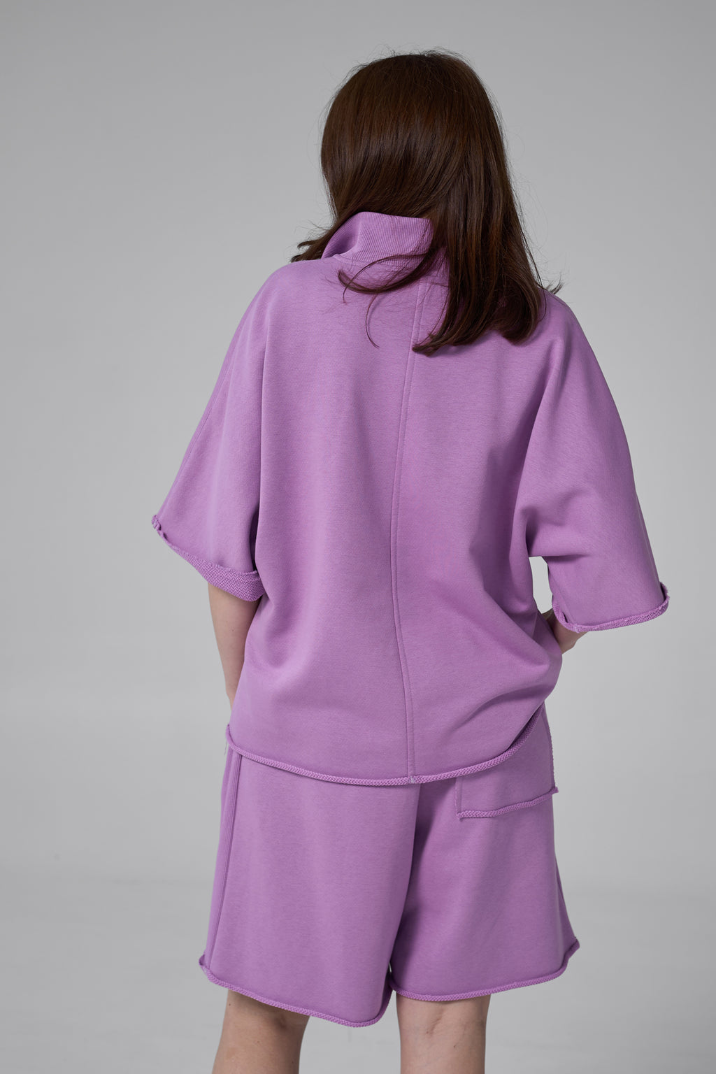 Person wearing a purple outfit on a gray background purple