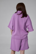 Person wearing a purple outfit on a gray background purple