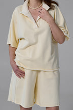 Person wearing a light yellow outfit with a matching top and shorts on a gray background yellow