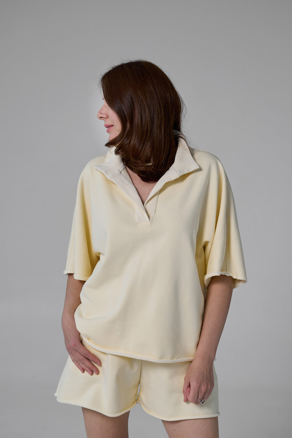 Woman wearing a light yellow outfit against a gray background yellow