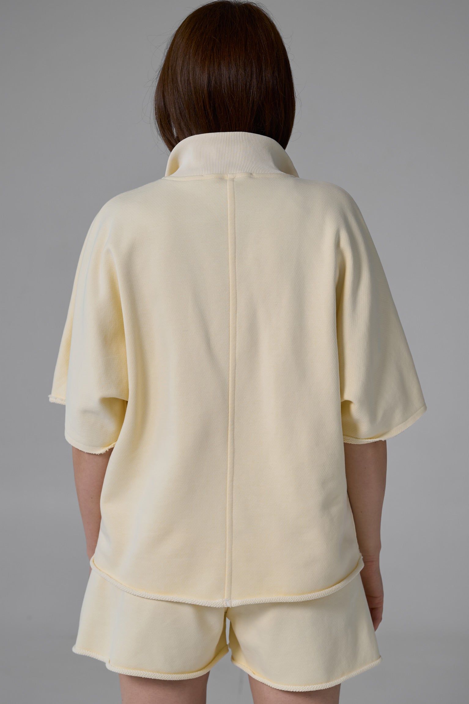 Person wearing a yellow outfit with a jacket and shorts on a gray background yellow