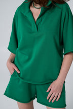 Green outfit with a top and shorts on a plain background emerald