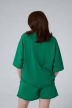 Person wearing a green outfit on a plain background emerald