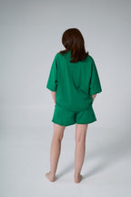 Person wearing a green outfit on a plain background emerald