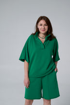 Woman wearing a green outfit against a plain background emerald