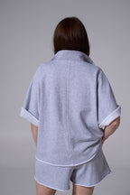 Person wearing a gray outfit with a plain background light blue
