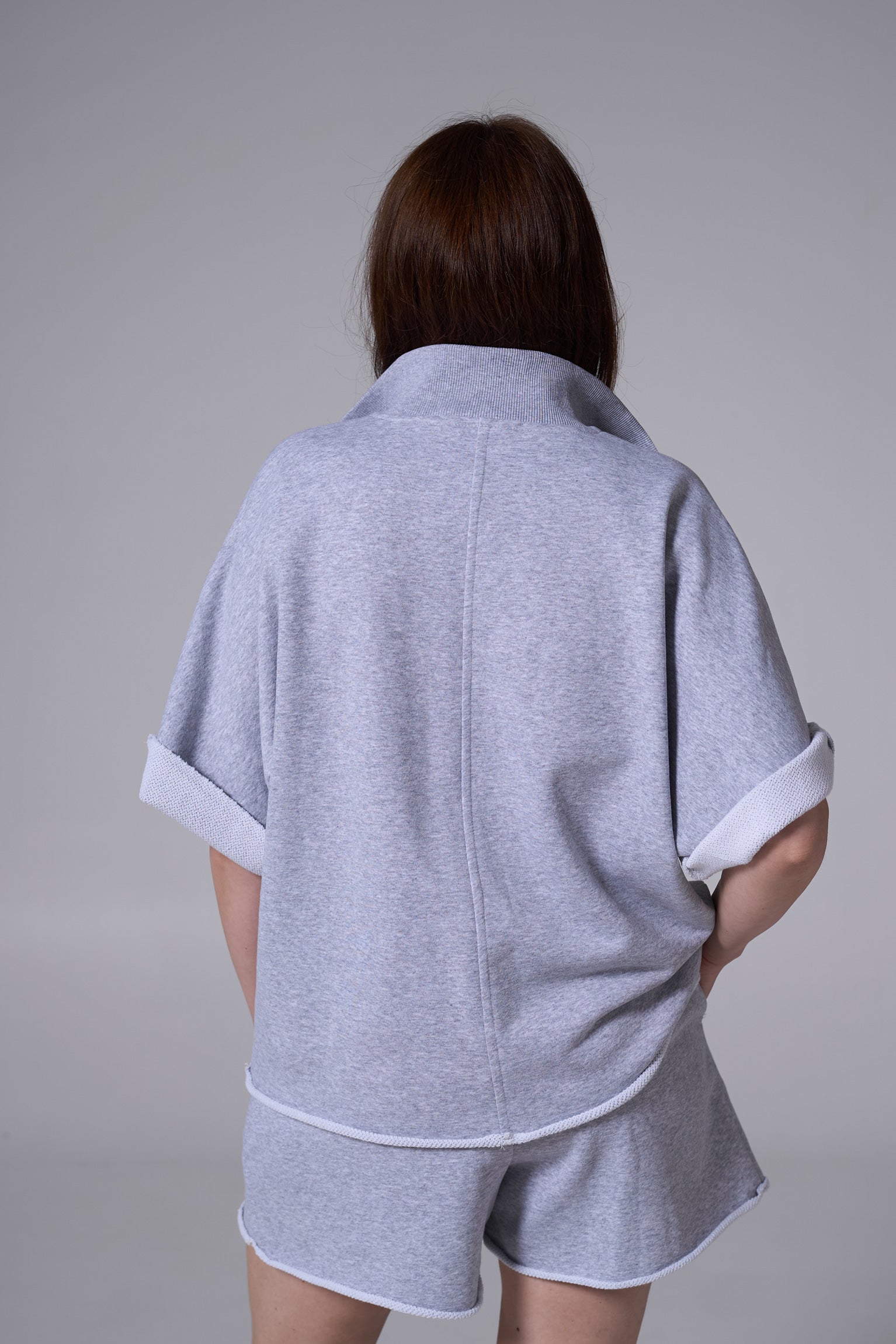 Person wearing a gray outfit with a plain background light blue
