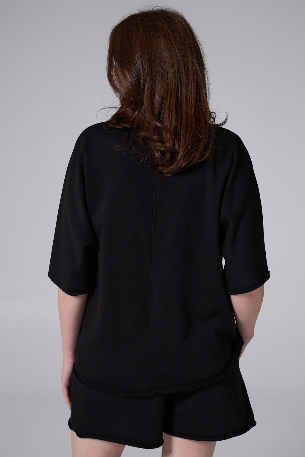 Person wearing a black outfit with a plain background black