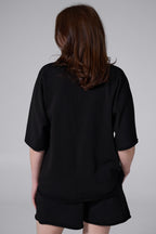 Person wearing a black outfit with a plain background black