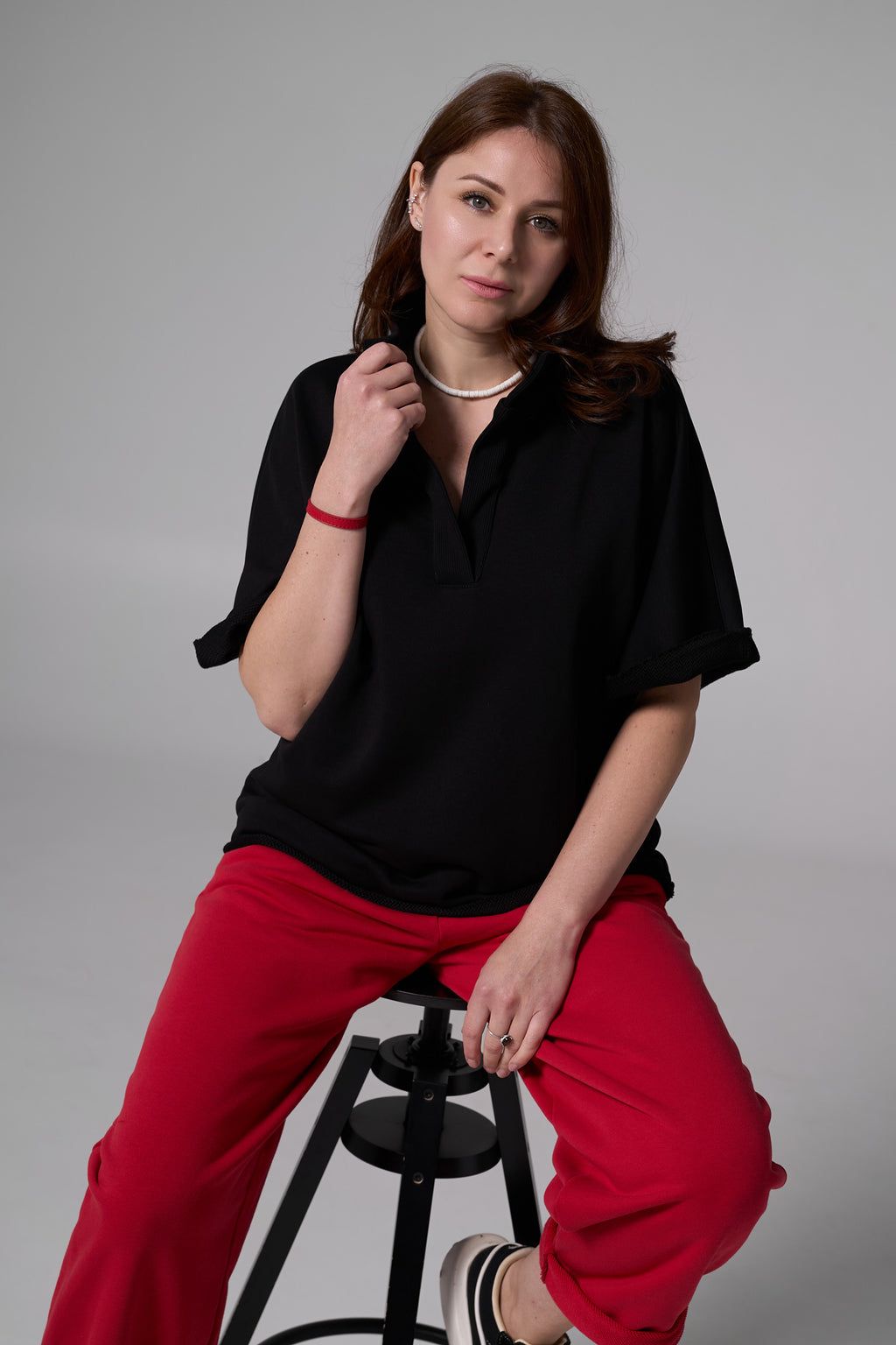 Woomen sitting on a chair in black tshirt  an red pants black