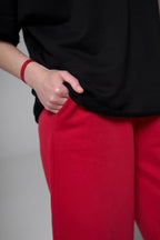 Person wearing a black top and red pants on a plain background black